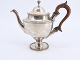 an antique silver teapot with a wooden handle on a white background