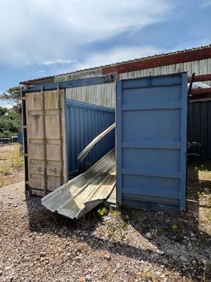 un conteneur bleu posé au milieu d'un champ de gravier