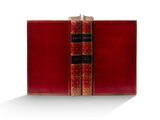 un vieux livre à la couverture rouge posé sur une surface blanche