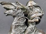 bronze statue of a man riding a horse with a helmet on