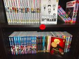 a book shelf with many dvds on it and a red rose