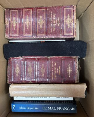 Plusieurs livres sont empilés les uns sur les autres dans une boîte en carton.