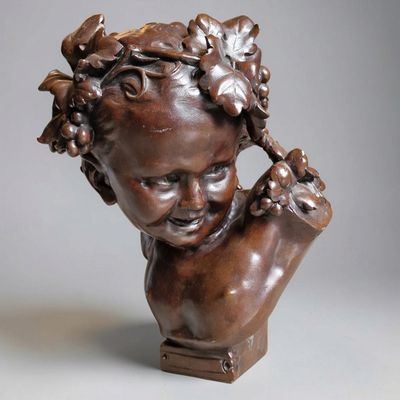 un buste antique en bronze représentant un enfant avec des grappes de raisin sur la tête
