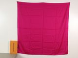 a pink blanket hanging on a wall next to a chair