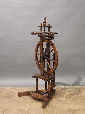an old spinning wheel on a wooden stand on a wooden floor