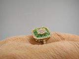 un gros plan sur la main d'une personne tenant une bague verte et blanche