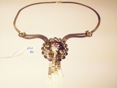 necklace with a gold chain and a flower with a red stone in the center
