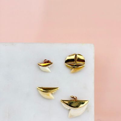 trois boucles d'oreilles en forme de poissons rouges posées sur un bloc de marbre