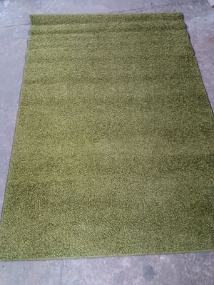 un tapis vert posé sur le sol d'une salle de bains, avec des toilettes en arrière-plan