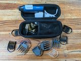 a hair clipper, combs, scissors, and other items in a case on a wooden table