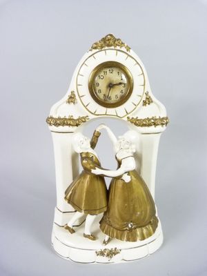 a white clock with a gold decoration on top of it