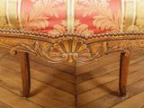 a red and gold upholstered bench on a wood floor