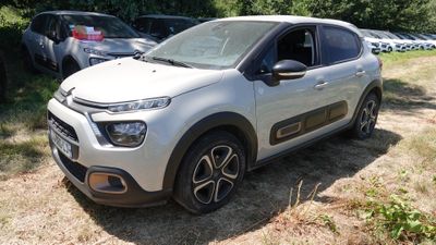 une Citroën blanche garée dans un champ, avec d'autres voitures en arrière-plan