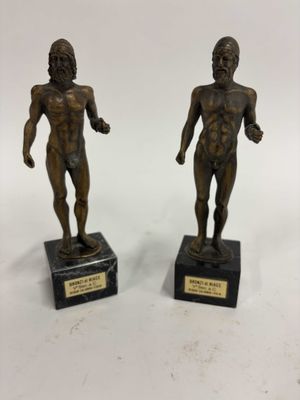 deux statues en bronze représentant un homme et une femme, posées sur des socles en marbre