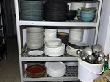 many plates and pans stacked on a shelf in a kitchen