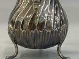 an antique silver plated pitcher with a handle on a stand