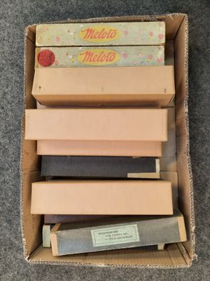 une boîte remplie de livres de toutes sortes, posée sur un tapis