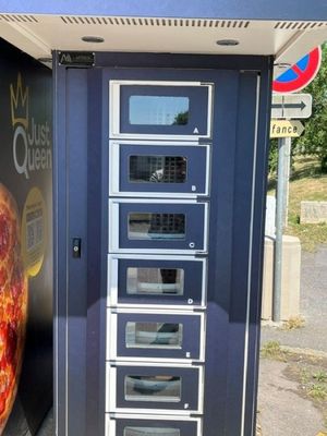 un distributeur automatique sur le côté duquel est posée une pizza