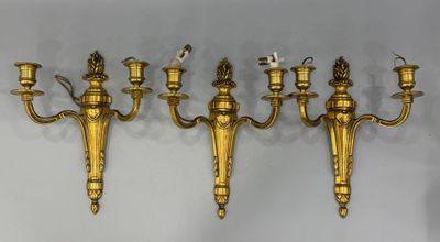 un ensemble de cinq appliques murales en laiton fixées sur un mur blanc