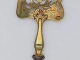 a gold and silver cake knife on a white surface