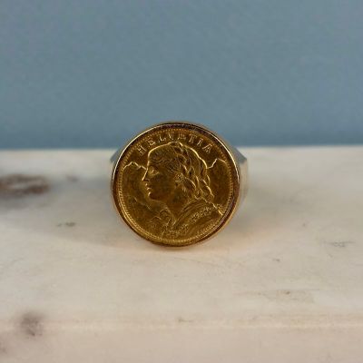 l'image d'une bague en or sur laquelle se trouve une pièce de monnaie