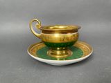 a green and gold cup and saucer on a saucer