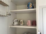 a shelf with cups and mugs on it in the corner of a kitchen