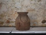 un vase marron posé sur une table devant un mur de pierre
