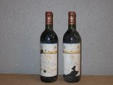 two bottles of wine sitting on a table next to each other