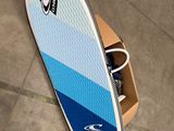 une planche de surf bleue et blanche posée par terre