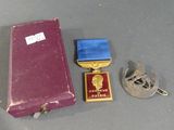 a purple case with a blue ribbon and a gold medal next to it