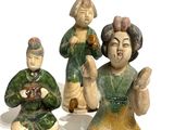 three figurines of asian people sitting on a white surface