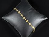un bracelet en chaîne d'or posé sur un coussin, sur fond noir
