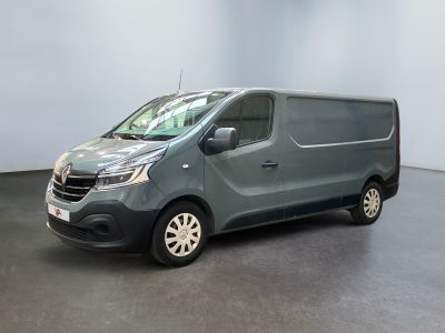 La camionnette grise est garée dans une grande pièce au sol noir.
