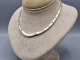 un mannequin blanc sur lequel est posé un collier en argent