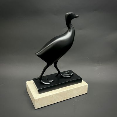 statue d'un oiseau noir posée sur un socle en marbre, sur fond gris