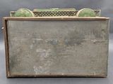 an old metal box with a green handle on a gray surface