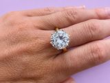 la main d'une femme tenant une bague en diamant sur un fond violet
