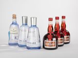quatre bouteilles d'alcool sont alignées les unes à côté des autres sur une surface blanche