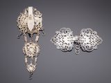 two pieces of silver jewelry on a gray surface