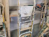 a pile of old chairs and ladders in a garage