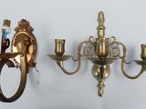 two wall sconces hanging on the wall next to a toothbrush and toothpaste