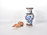 un vase bleu et blanc posé à côté d'une petite figurine