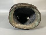 a bronze vase with a hole in it on a white surface
