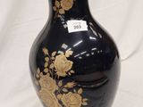 a black vase with gold flowers on it on a white background