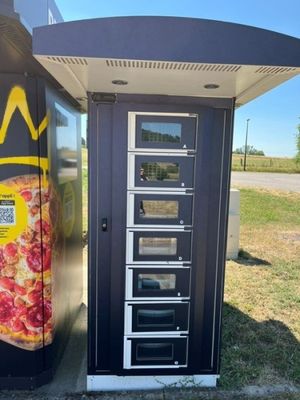 un distributeur automatique sur le côté duquel est posée une pizza