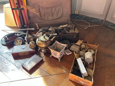une valise remplie de vieux objets posée par terre