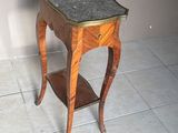 une petite table en bois avec un plateau en marbre, posée sur un sol carrelé