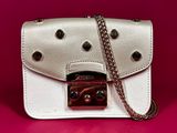 a white purse with a chain hanging from it on a pink background
