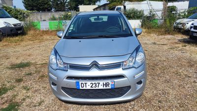 a small silver car parked in a lot with other cars in the background